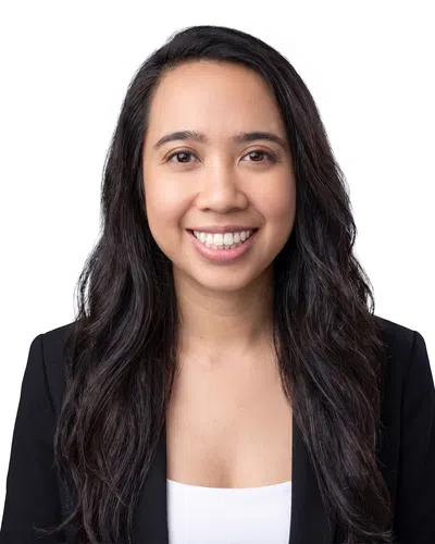 Smiling woman with long dark hair wearing a black blazer and white top against a white background