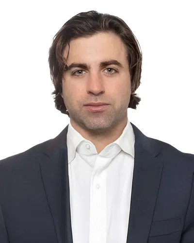 Professional man with medium-length brown hair wearing a navy suit jacket and white shirt against white background