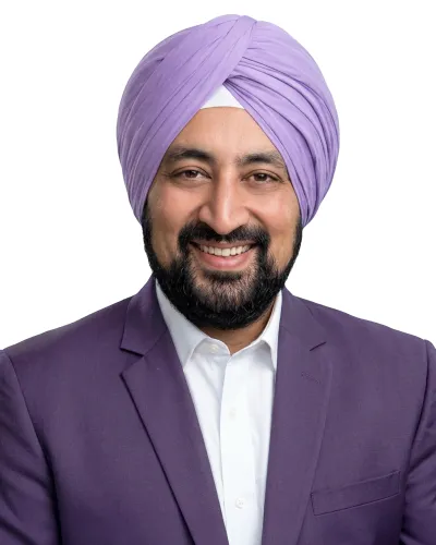 Smiling man wearing a lilac turban and matching suit jacket with a white shirt on a white background