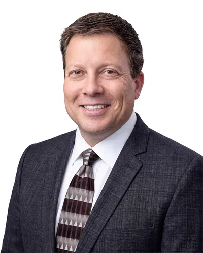 Smiling businessman wearing a dark suit and patterned tie on a white background