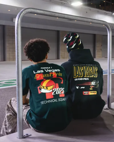 Two people sitting with backs showing Las Vegas Grand Prix 2025 apparel with colorful graphics and logos.