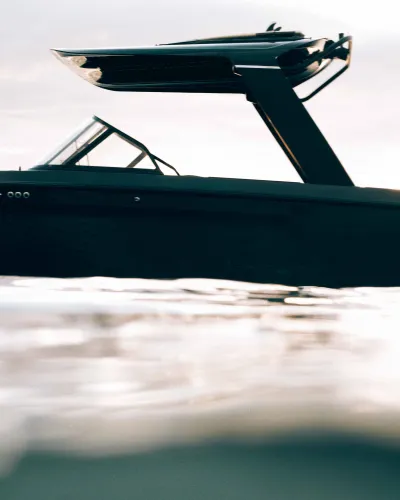 Sleek black ARC boat floating on calm water with modern design and covered upper deck under cloudy sky.