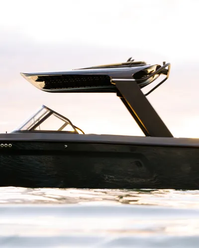Sleek black ARC luxury speedboat floating on calm water with modern design under cloudy sky.
