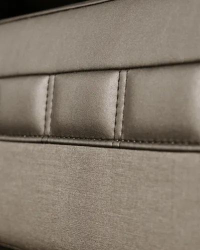Close-up of light brown leather and fabric upholstery with detailed stitching and textured surfaces.