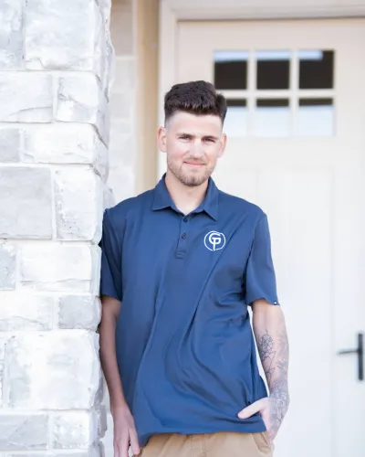 A man in a navy polo shirt poses by a stone wall, showcasing a casual outdoor look.