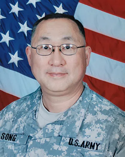 Portrait of a U.S. Army soldier wearing digital camouflage uniform with American flag backdrop.