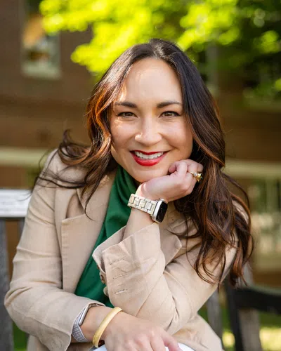 Smiling woman with straight shoulder-length hair wearing a black LumiVita spa uniform against a light background
