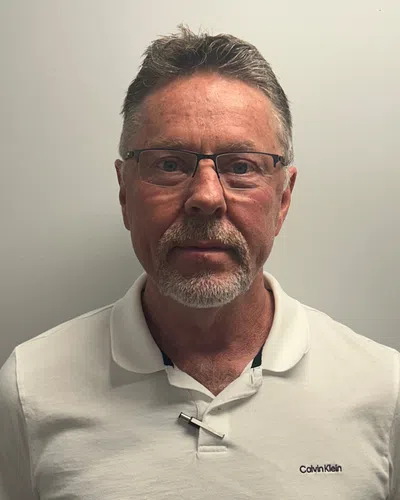 Middle-aged man with glasses and gray hair wearing white Calvin Klein polo shirt against a plain background