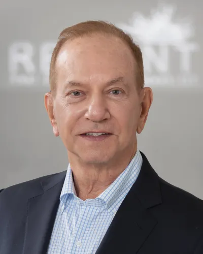 Professional portrait of a middle-aged man in a blue checked shirt and dark blazer with a neutral background.