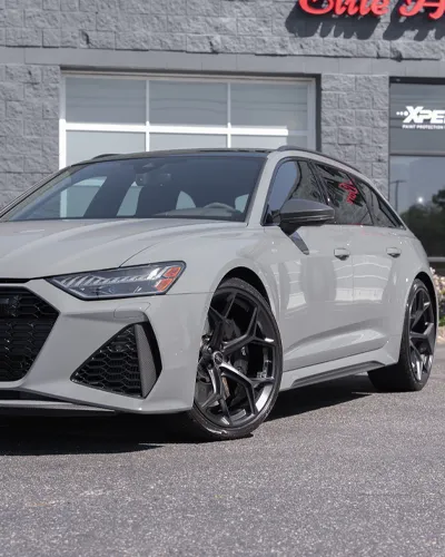Gray luxury station wagon with sleek design and black alloy wheels parked outside a building.