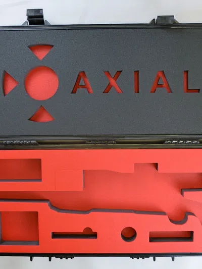 Black gun case with red foam interior cutouts and AXIAL logo on the lid, designed for firearm storage.