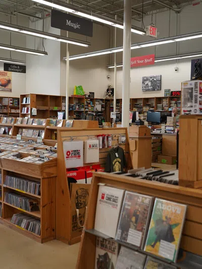 Interior view of a well-organized music and media store with wooden shelves and various CDs and collectibles.