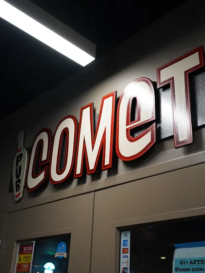 Comet Lanes bowling alley sign above double doors in a dimly lit hallway with bowling pin graphics.