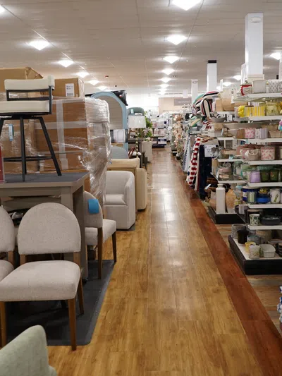 Aisle in a home goods store with furniture on the left and shelves of blankets and textiles on the right