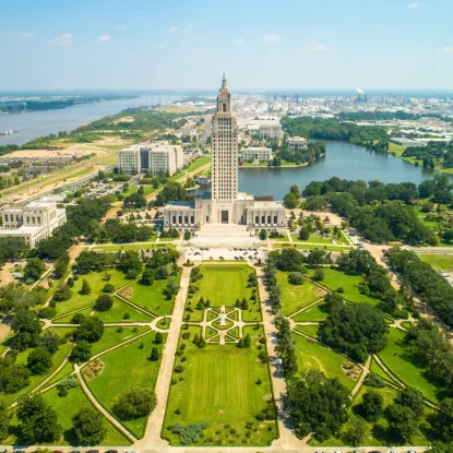 a large building with a tower surrounded by trees and a body of water