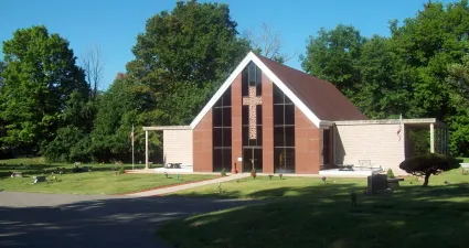 a brick building with a lawn and trees in the front