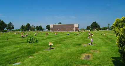 a large grassy field with people in it and a building in the background