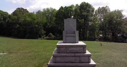 a stone statue in a grassy field