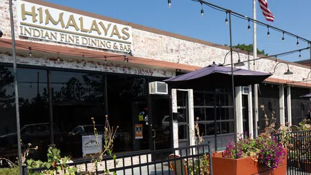 Exterior view of Himalayas Indian Fine Dining & Bar with outdoor seating and decorative plants under string lights