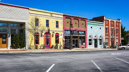 Colorful historic downtown buildings with bright facades under a clear blue sky and empty street in foreground