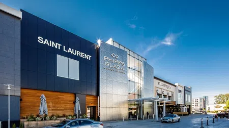 Exterior view of Phipps Plaza shopping mall featuring Saint Laurent store under clear blue sky.