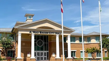 Front view of A. Max Bacon City Hall with columns, flags, and clear blue sky on a sunny day
