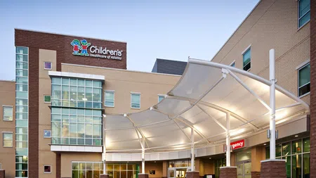 Entrance of Children's Healthcare of Atlanta hospital with modern canopy and emergency sign at dusk