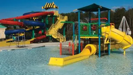 Colorful water park with slides, splash areas, and a shallow pool under a clear blue sky.