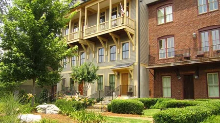Residential townhouses with balconies and lush green landscaping under a clear sky