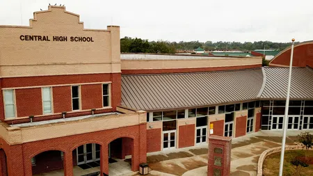 Front view of Central High School building with red brick and beige facade under overcast sky.