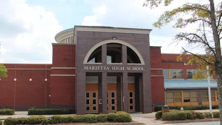 Front entrance of Marietta High School with brick facade, arched doorway, and surrounding greenery on a clear day.
