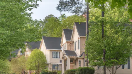 Suburban street lined with houses and lush green trees during daytime on a clear day