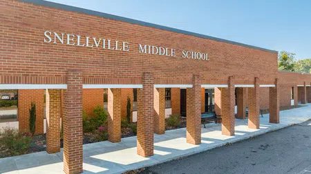 Front view of Snellville Middle School brick building with columns and clear blue sky on a sunny day.