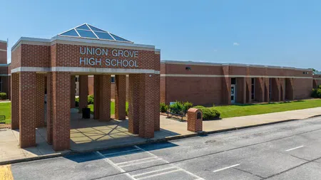 Entrance of Union Grove High School with brick pillars and clear blue sky above the building.