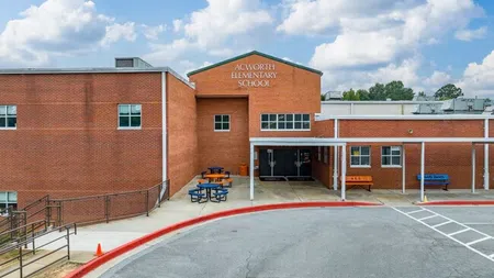 Exterior of Acworth Elementary School building with outdoor seating and blue sky with clouds.