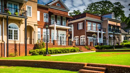 Row of colorful brick townhouses with green lawns and clear blue sky on a sunny day