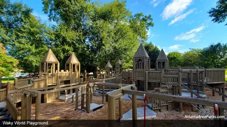 Wills Park Waky World Playground with wooden structures, towers, slides, and green trees under a blue sky