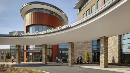 Modern Northeast Georgia Medical Center with curved entrance and stone pillars under clear sky