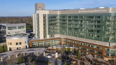 Aerial view of Northeast Georgia Medical Center with modern glass facade and surrounding landscape under clear sky.