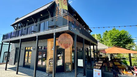 Two-story restaurant Sweet Octopus with outdoor seating, black railing, and sunny sky on a clear day