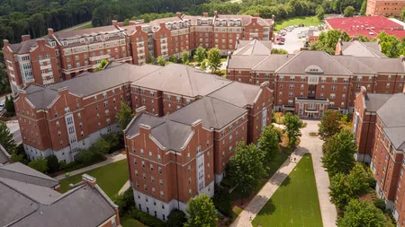Aerial view of a large college dormitory complex with red brick buildings and green spaces on campus.