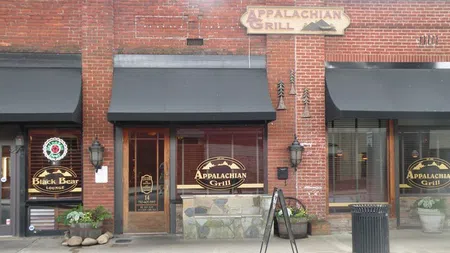 Brick building exterior with Appalachian Grill restaurant signs and black awnings on a sidewalk.