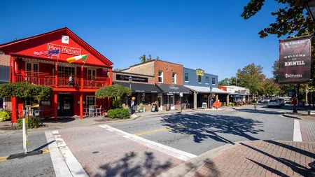 Sunny street view of historic Roswell with colorful shops and outdoor seating under clear blue sky