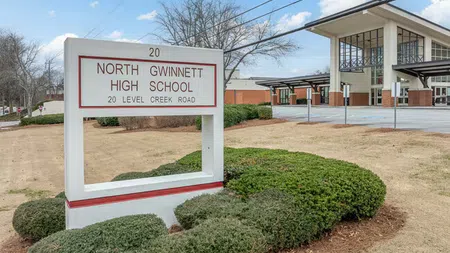 North Gwinnett High School sign with building and parking area in background under blue sky