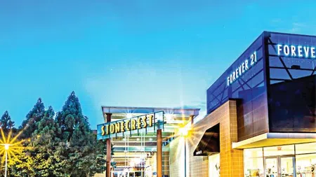 Stonecrest shopping center entrance at night with illuminated Forever 21 store and trees under a clear sky