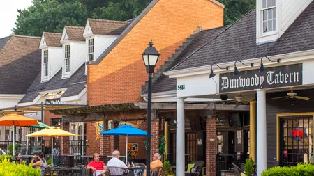 Outdoor seating at Dunwoody Tavern with colorful umbrellas and diners enjoying a sunny day
