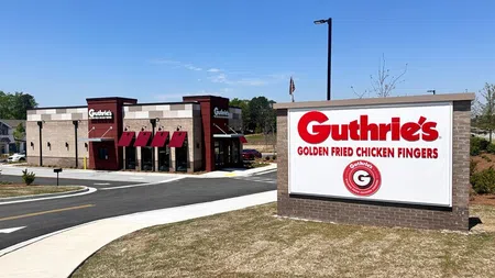 Guthrie's restaurant building with red awnings and signage advertising golden fried chicken fingers under a clear blue sky.