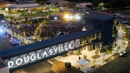 Aerial night view of a crowded outdoor event at Douglasville with illuminated signage and stage lights.