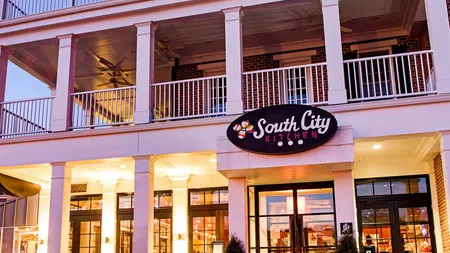 Facade of South City Kitchen restaurant with lit entrance and white columned porch at dusk.