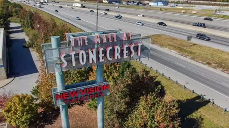 Aerial view of The Mall at Stonecrest sign and New Vision Theatres next to a busy multi-lane highway with cars.